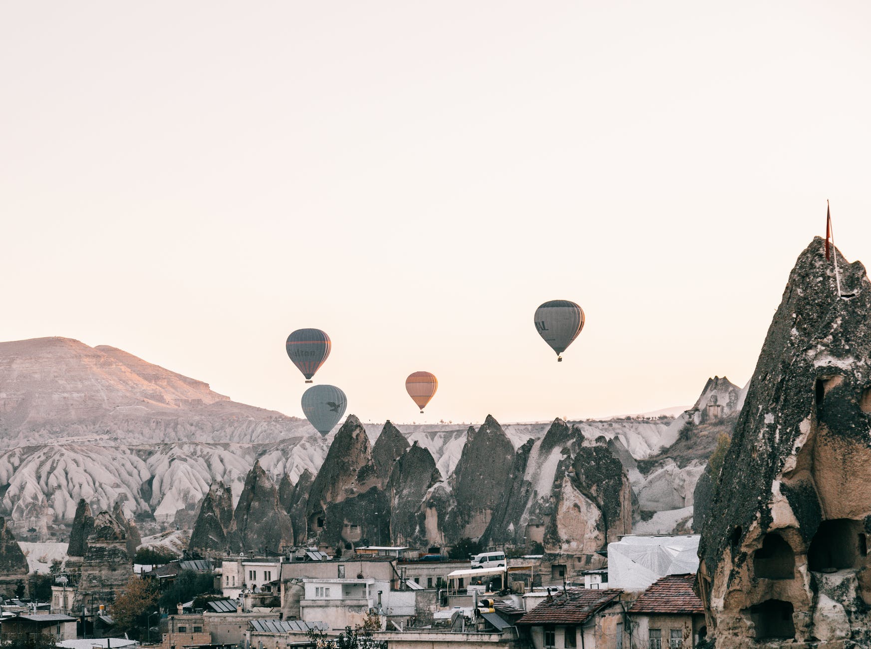 air balloons flying over town located amidst rocky formations at sundown